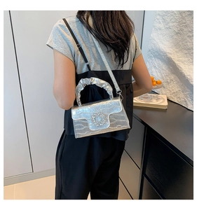 Detail of silver crocodile texture handbag featuring sparkling crystal buckle and pleated handle