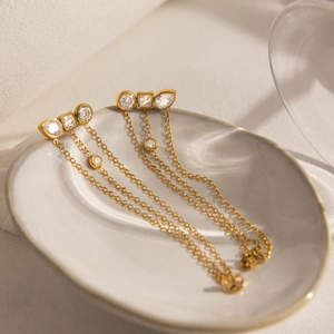 Detail of 18K gold tassels earrings with clear zircon stones on ceramic tray