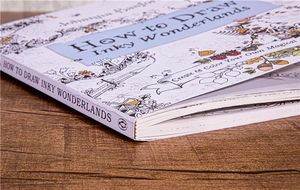 Detailed close-up of How to Draw Inky Wonderlands book on a dark wood grain background