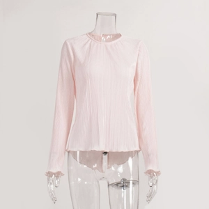 Detail of light pink pleated fabric showing delicate texture and ruffled sleeve edges