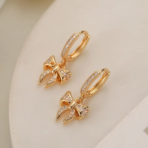 Elegant 18K gold plated bow earrings with sparkling cubic zirconia on a minimalist stand