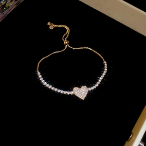 Detail of a sparkling heart charm bracelet with gold finish and adjustable slider clasp