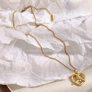 Detail of 18K gold-plated stainless steel necklace with interlocking heart pendant on paper