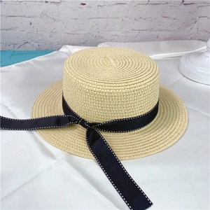 Detailed macro shot of a beige summer straw boater hat featuring a black dotted ribbon