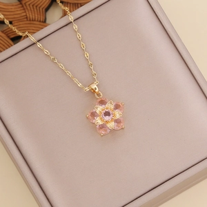 Layered gold necklace with pink zircon flower pendant on a pink leather jewelry box