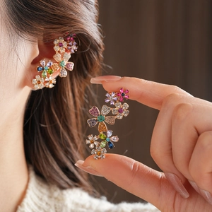 Nahaufnahme vergoldeter Blumen-Ohrclips mit bunten Zirkonia, getragen von einem Modell