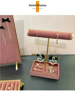 Detail view of pearl heart earrings and gold necklace set on a pink velvet jewelry display