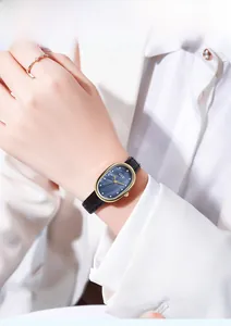 Detail of GEDI watch with oval gold case and blue mother-of-pearl dial on a black leather strap