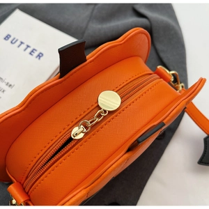 Macro detail of orange Saffiano leather pumpkin bag with gold metal zipper and chain