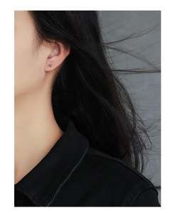Close-up of minimalist square zircon stud earrings worn by a model in black and white
