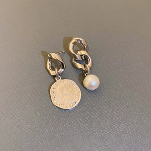 Asymmetric silver chain earrings with Swiss coin and pearl pendants on grey surface