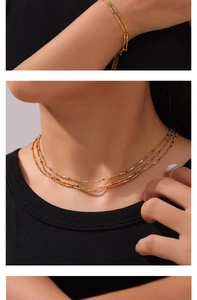 Close-up of layered gold titanium necklace and bracelet set with colorful bead accents