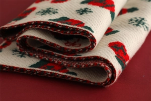 Close-up of soft knitted scarf featuring red rose and green snowflake patterns