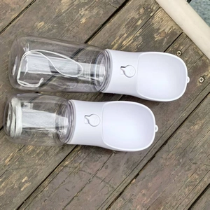 Close-up of portable pet water bottles in two sizes with wrist straps on wood floor