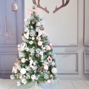 Close-up of wool felt star ornaments and pink velvet bows on a snow-flocked Christmas tree