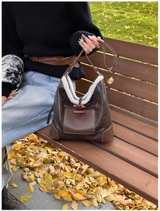 Detail of vintage brown leather tote bag with white faux fur trim and horn buckle