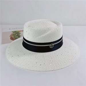 Detail of white straw sun hat featuring silver sequins and black ribbon with gold buckle