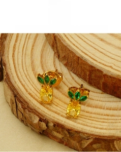 Detail shot of gold-plated pineapple stud earrings with green and yellow crystals