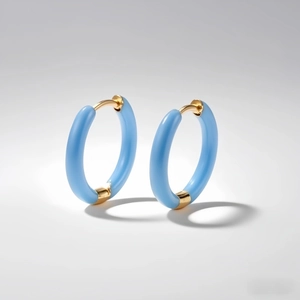 Macro shot of light blue enamel hoop earrings with polished gold-plated buckle