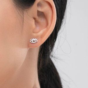 Boucles d'oreilles clous œil bleu en argent s925 avec cils portées par un modèle