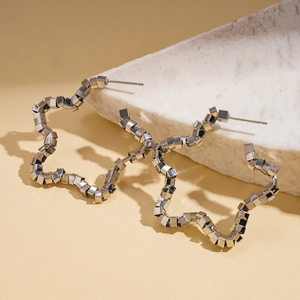 Silver hollow star earrings made of small metal cubes on a marble background