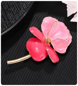 Close-up of vintage enamel iris brooch with pink petals and golden stem on black background