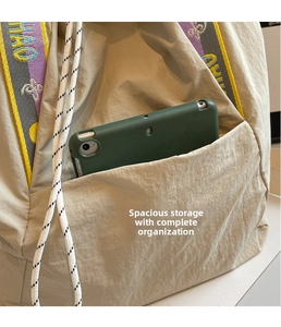 Detalle de bolso tote de lona con bolsillo frontal grande y correa tejida de colores