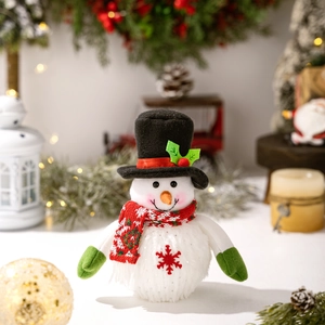 Detail of plush Christmas snowman figurine with red scarf and glowing warm lights background