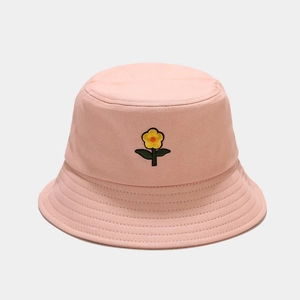 Dettaglio del ricamo a piccoli fiori gialli sul cappello a secchiello in tela rosa con cucitura