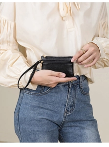 Close-up of a black lychee texture mini coin purse with double gold zippers and wrist strap