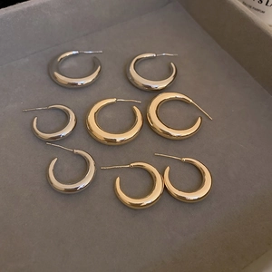 Detailed flat lay of C-shaped gold and silver hoop earrings on a velvet jewelry tray