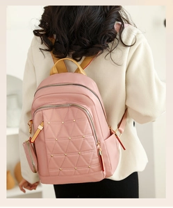 Mochila Oxford rosa acolchada con remaches dorados en modelo en un interior luminoso