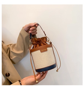 Close-up of drawstring bucket bag made of canvas and contrast leather with top handle