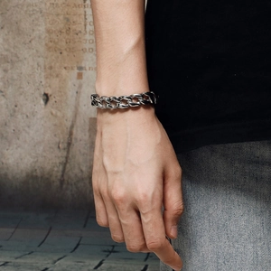 Polished silver titanium steel Cuban chain bracelet worn on a wrist in an urban setting