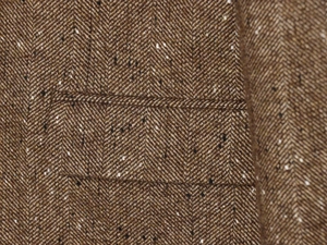 Macro shot of brown herringbone tweed fabric texture with detailed pocket stitching