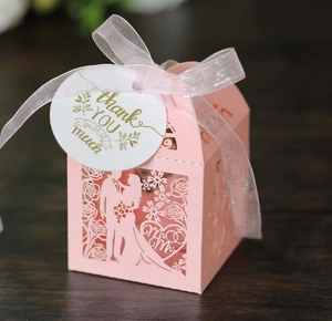 Detail of pink laser-cut wedding favor box with Mr & Mrs motif and thank you tag
