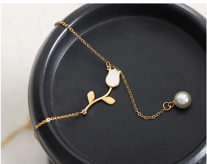 Detailed close-up of a vintage tulip pendant with pearl accent on 18K gold-plated chain