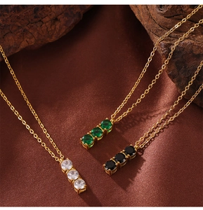 Detail of three-stone pendant necklaces in green, black, and clear on silk background