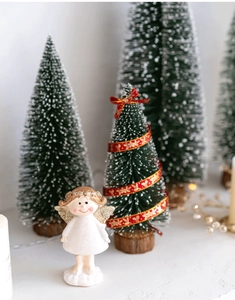 Miniature Christmas scene with a white angel figurine and snow-covered green flocked pagoda trees