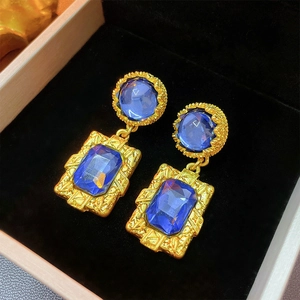 Macro detail of vintage gold earrings with blue rectangular gemstones in jewelry box