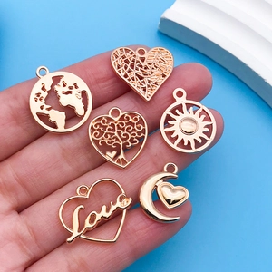 Macro shot of six rose gold charms including heart and map designs on a hand