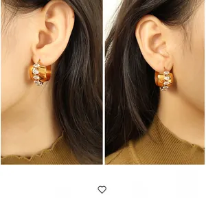 Exaggerated C-shaped gold hoop earrings with white oval zirconia inlay on model