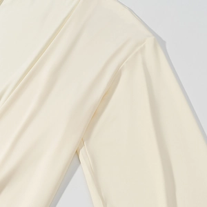 Dettaglio della trama in maglia crema e taglio della manica con drappeggio fluido