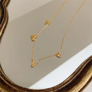 Elegant gold 925 silver necklace with LOVE heart pendants on a vintage mirror surface