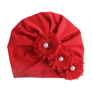 Detailansicht der roten Baby-Turbanmütze mit drei Stoffblumen und weißen Perlen