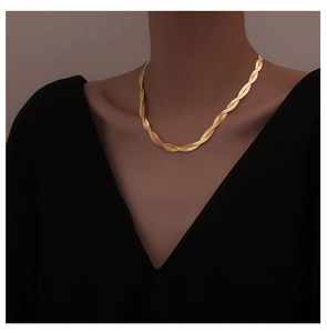 Close-up of a gold-plated twisted snake bone necklace on a model wearing black