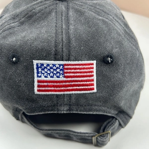 Close-up of charcoal gray cotton baseball cap with US flag embroidery and metal buckle