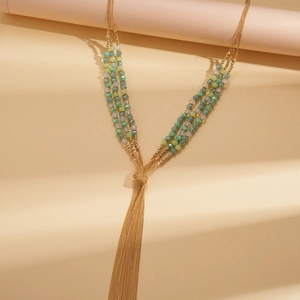 Detailed view of bohemian triple-layer beaded necklace with green tassels and gold chains