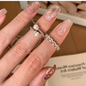 Detail of silver twisted rings with pearl and zircon inlay worn on an elegant hand