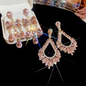 Boucles d'oreilles nœud dorées avec cristaux roses sur fond de velours luxueux